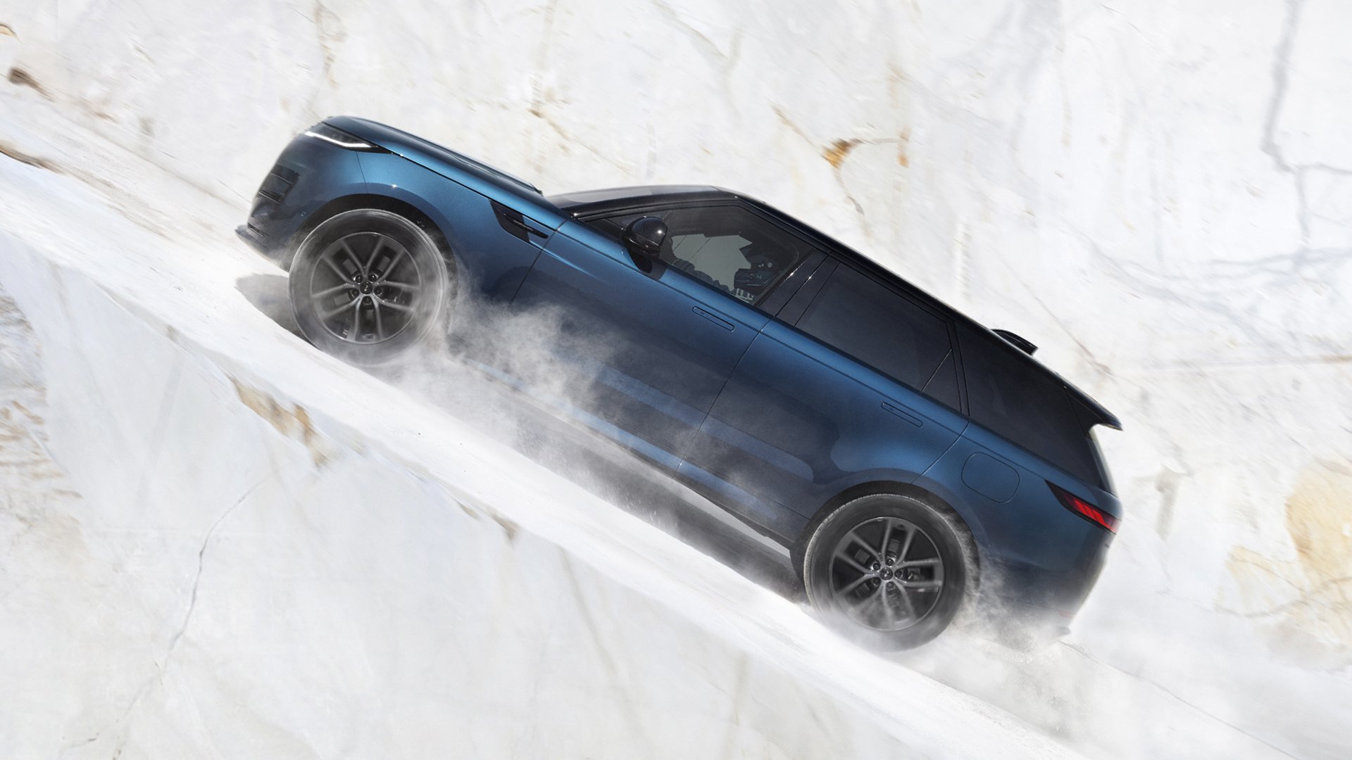 Granatowy Range Rover Sport Electric wjeżdżający na stromą marmurową skarpę.